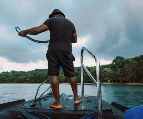 Man on a boat pulling up its anchor on Príncipe Island