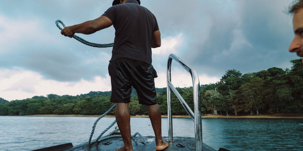 Man on a boat pulling up its anchor on Príncipe Island